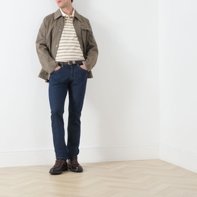 Model wearing Seven Jeans Sundown straight jeans in dark indigo, styled with a striped polo, brown jacket and lace-up boots.