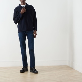 Model wearing Seven Jeans Indigo Minty straight jeans, styled with a navy half-zip knit and black leather shoes.