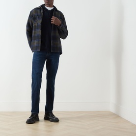 Model wearing Seven Jeans Indigo Minty straight jeans, styled with a dark plaid overshirt, black jumper and black leather shoes.