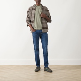 Model wearing Seven Jeans Slimmy Mid-Rise Tapered Jeans in Signal blue with plaid overshirt, sage tee and grey trainers.