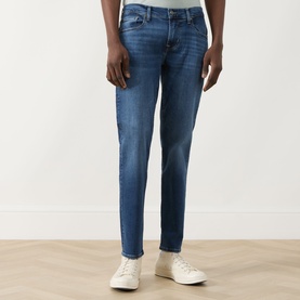 Model wearing Seven Jeans Slimmy Mid-Rise Tapered Jeans in Signal blue with whiskering and faded details, styled with white trainers.