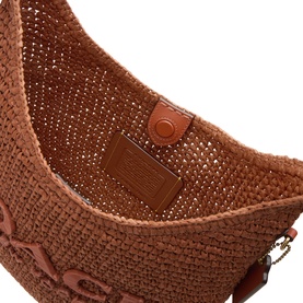 Coach Brooklyn 28 Woven Shoulder Bag in clay paper straw, close-up of open interior showing magnetic button closure and branded logo patch