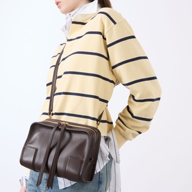 Model carrying Loewe Amazona 180 Small Top Handle Bag in Dark Chestnut, grained leather, gold-tone hardware, worn crossbody with striped knitwear