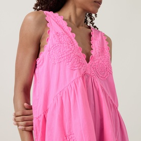 Model wearing Juliet Dunn hot pink cotton sleeveless dress with scalloped edges and crochet lace V-neckline detail