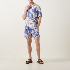 Model wearing OAS Mystea Rocco Printed Shirt in blue tropical print with matching shorts and brown slider sandals.