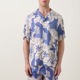 Model wearing OAS Mystea Rocco Printed Shirt in blue abstract figure print, notched collar, short sleeves, paired with matching shorts.