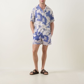 Model wearing OAS Mystea Rocco Printed Shirt in blue tropical print, styled with matching shorts and brown sandals.
