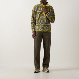 Model wearing Columbia Helvetia Half-Buttoned Fleece Sweatshirt in Mossy Green with geometric print, styled with olive cargo trousers and trainers.