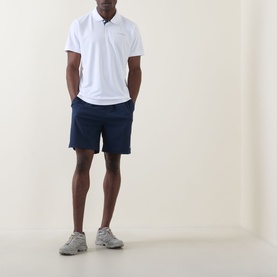 Model wearing Columbia Utilizer&trade; Logo Polo Shirt in white with navy shorts and grey trainers.