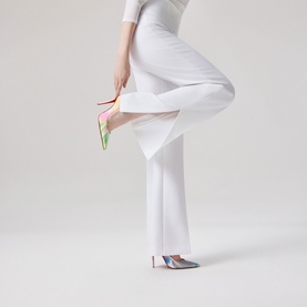 Model wearing Christian Louboutin heels in multi colourway, pointed toe stiletto with iridescent upper, styled with white wide-leg trousers