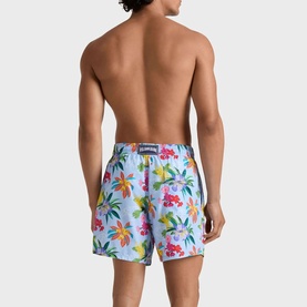 Model wearing Vilebrequin swim shorts in Fleur de Lin, featuring a vibrant tropical floral print, rear view