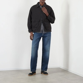 Model wearing Edwin Chaos Water-Resistant Jacket in black, styled with blue straight-leg jeans and dark loafers.