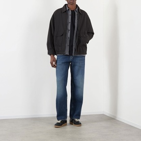Model wearing Edwin Chaos Water-Resistant Jacket in black with blue straight-leg jeans and black leather shoes.