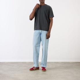 Model wearing Edwin Axiom Logo T-Shirt in dark grey with light wash straight-leg jeans and red suede trainers.