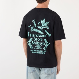 Model wearing Edwin Hardware Store Logo T-Shirt in black, showing enlarged turquoise graphic back print, paired with light blue jeans.