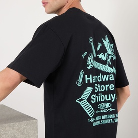 Model wearing Edwin Hardware Store Logo T-Shirt in black, back view showing enlarged teal Shibuya graphic print, crew neck, short sleeves.