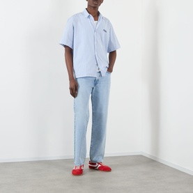 Model wearing Edwin Loose Straight Leg Jeans in light blue with faded details, styled with a light blue shirt and red trainers.