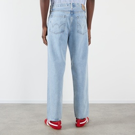 Model wearing Edwin Loose Straight Leg Jeans in light blue wash, rear view showing logo badge, styled with red trainers.