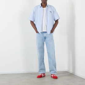 Model wearing Edwin Loose Straight Leg Jeans in light used blue with a light blue shirt and red trainers.