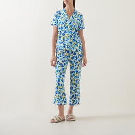 Model wearing Kate Spade Blooming Garden pyjamas in blue floral print, short-sleeve shirt and cropped trousers, styled with beige sandals