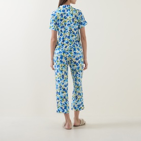 Model wearing Kate Spade Blooming Garden pyjamas, blue and yellow floral print short-sleeve top and cropped trousers, back view.