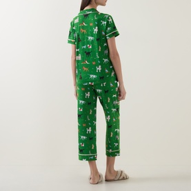 Model wearing Kate Spade Dog Park pyjamas in green with all-over dog print, short-sleeve top and cropped trousers, back view.