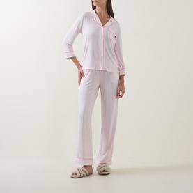 Model wearing Kate Spade Christy Shirting Stripe pyjamas in pink and white, with contrasting trim, paired with fluffy slippers.