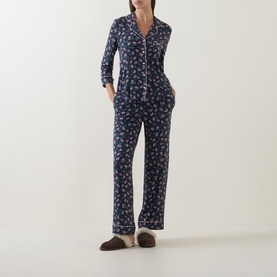 Model wearing Kate Spade Lively Blooms Tossed pyjamas in navy floral print, styled with brown mule slippers.