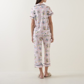 Model wearing Kate Spade City Stroll pyjamas in pink novelty print, cropped trousers and short-sleeve shirt with navy trim, back view