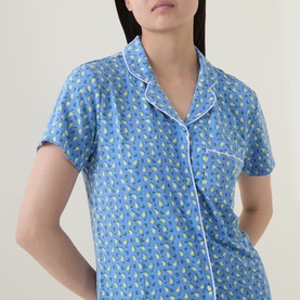 Model wearing Stripe & Stare Sorento Lemon pyjama shirt in blue with lemon print, white piping trim, short sleeves and chest pocket.