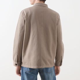 Model wearing Nudie Jeans Barney Worker Overshirt in Mud, rear view, showing tonal stitching and straight hem, styled with blue jeans.