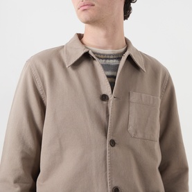 Model wearing Nudie Jeans Barney Worker Overshirt in Mud, button-front with chest pocket, styled over a grey marl knit