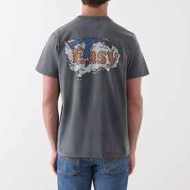 Model wearing Nudie Jeans Roy Take It Easy Logo T-Shirt in Antracite, showing rear graphic print, styled with blue jeans