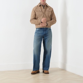 Model wearing Nudie Jeans Casual Jacket in G13 Mud, styled with blue wide-leg jeans and brown boots