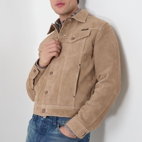 Model wearing Nudie Jeans Casual Jacket in G13 Mud, suede-effect fabric with button front, styled with blue jeans and checked shirt.
