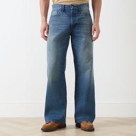 Model wearing Nudie Jeans 3049 loose jeans in Blue Painter, styled with tan leather boots