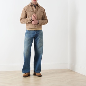 Model wearing Nudie Jeans 3049 Loose Jeans in Blue Painter, styled with a tan suede jacket and brown shoes.