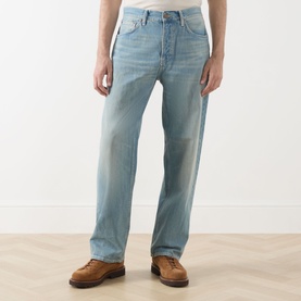 Model wearing Nudie Jeans Tuff Tony Straight Leg Jeans in Drift Wood, loose fit with faded whiskering details, styled with brown leather boots.