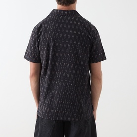 Model wearing Nudie Jeans Reg Shirt in R22 Multi, black with all-over geometric print, short sleeves, shown from the back