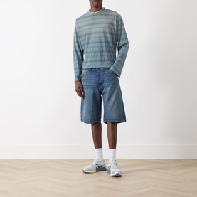 Model wearing Nudie Jeans Zeb High-Rise Wide Leg Denim Shorts in Blue Painter, wide-cut fit, styled with striped long-sleeve top and white socks.