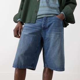 Model wearing Nudie Jeans Zeb High-Rise Wide Leg Denim Shorts in Blue Painter with wide-cut legs and faded whiskering details, styled with a striped