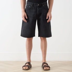Model wearing Nudie Jeans 3049 denim shorts in Night Dune black wash, styled with brown leather Birkenstock sandals.