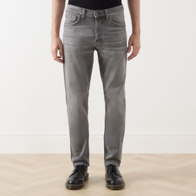 Model wearing Nudie Jeans Solid Ollie Mid-Rise Slim Leg Jeans in Pale Ash with slim-cut legs and faded details, styled with black leather shoes.