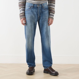 Model wearing Nudie Jeans 3049 straight jeans in Slow Drive mid blue wash, styled with a striped jumper and brown leather boots.