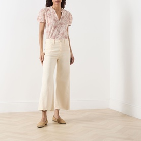 Model wearing Paige Anessa Front Pockets High-Rise Wide Leg Jeans in Butter Yellow, cropped raw hem, styled with pink floral blouse and tan mules.
