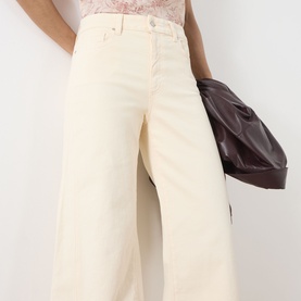 Model wearing Paige Anessa Front Pockets High-Rise Wide Leg Jeans in Butter Yellow, cropped wide leg, raw hem, styled with a burgundy bag.