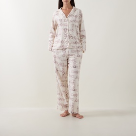 Model wearing DKNY Blonde Logo Plaid pyjamas, long-sleeve button-front top and wide-leg trousers in cream logo print.