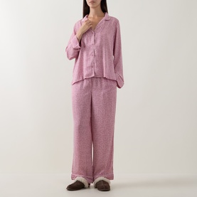 Model wearing DKNY Monogram Satin Long-Sleeved Pyjama Set in Dusty Mauve, featuring notched collar top and straight-leg trousers with piped trims.