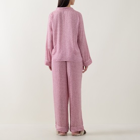 Model wearing DKNY Monogram Satin Long-Sleeved Pyjama Set in Dusty Mauve, showing rear view of long-sleeve top and straight-leg trousers.