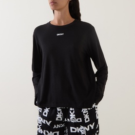 Model wearing DKNY Black Logo Plaid pyjama set with long-sleeve top and monogram print trousers.